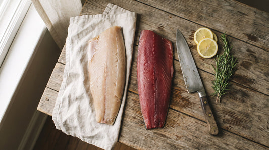 Side-by-side albacore and skipjack tuna fillets on a wooden board