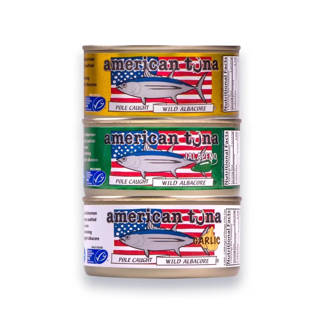 Three cans of American Tuna stacked on a white background