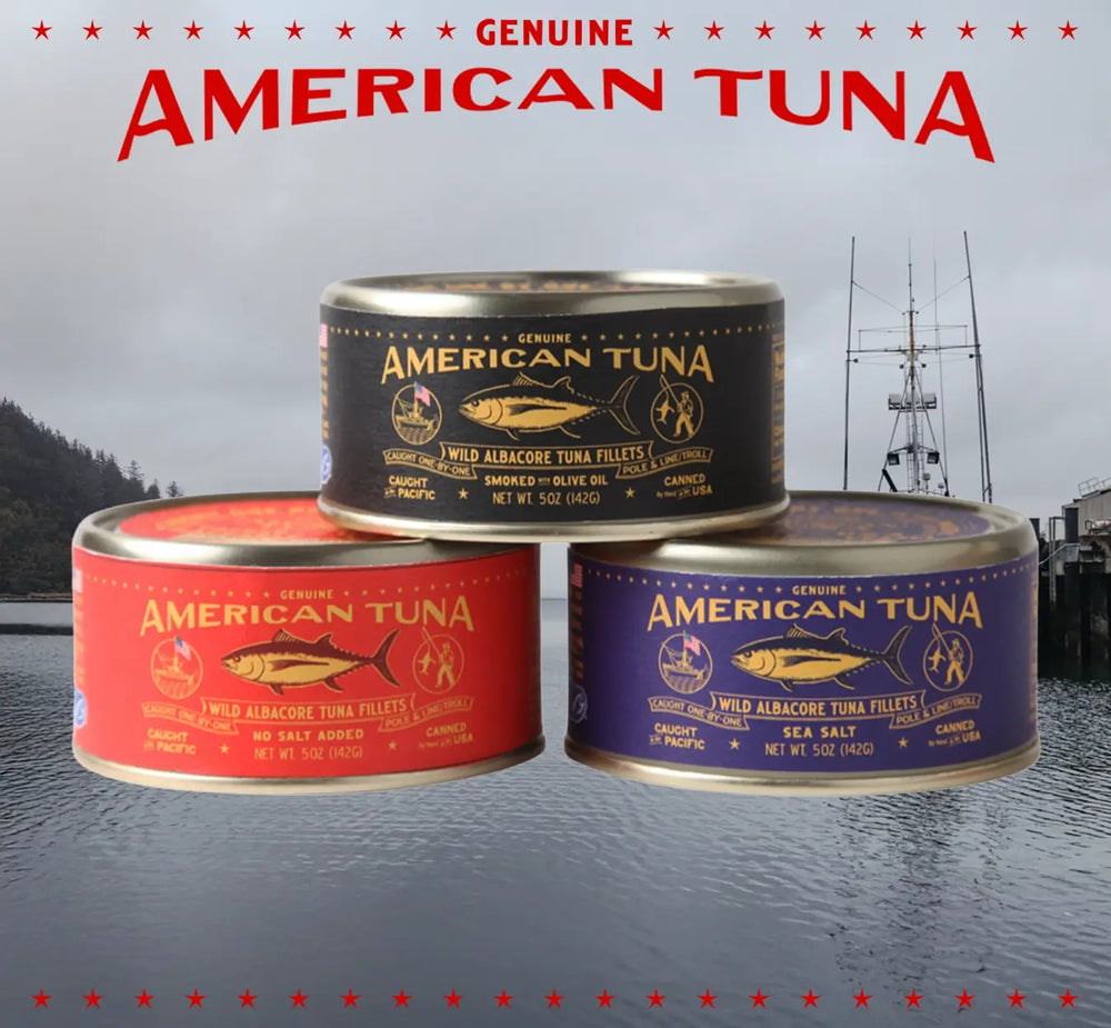 Stack of American Tuna wild albacore tuna cans in different varieties, shown in front of a Pacific Northwest fishing harbor and vessel.